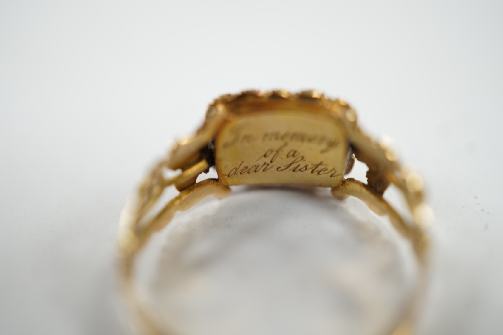 A 19th century yellow metal, seed pearl and plaited hair set mourning ring, the ring head verso inscribed 'In memory of a dear sister', size J, gross weight 1.4 grams. Condition - fair